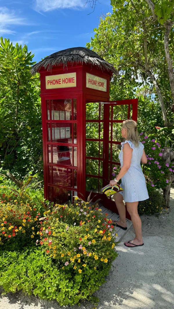 Angélique bij een rode telefooncel tussen de bloemen op de Malediven