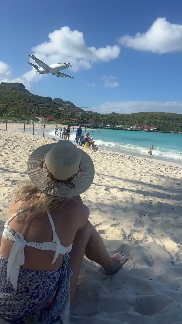 Angélique op het strand van Saint-Barthélemy terwijl een vliegtuigje overvliegt