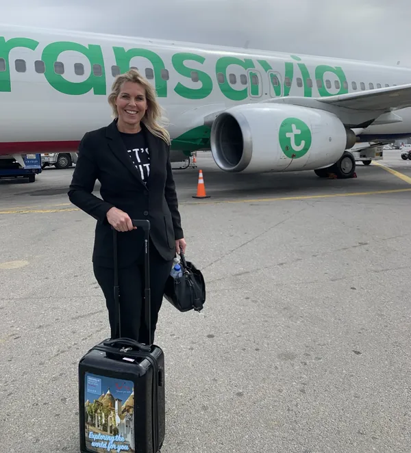 Angélique met haar koffer op het platform voor een vliegtuig van Transavia