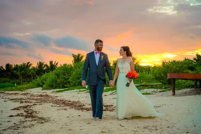 Bruidspaar hand in hand op het strand bij zonsondergang
